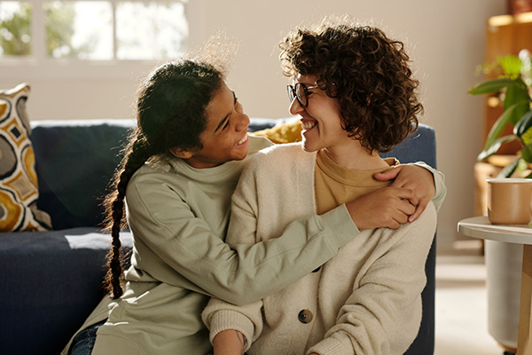 happy teenage girl embracing her mom while they spending time together at home